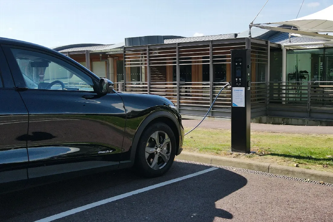 An electric vehicle beside charging infrastructure at a Lawn Tennis Association site